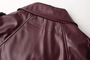 Detailed close-up of dark red faux leather jacket collar and shoulder stitching craftsmanship