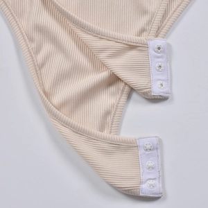 Detail of ribbed beige bodysuit featuring three functional white snap buttons at the crotch