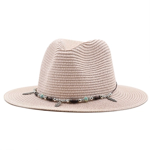 Close-up of pink straw hat with turquoise beads and vintage feather metal pendants