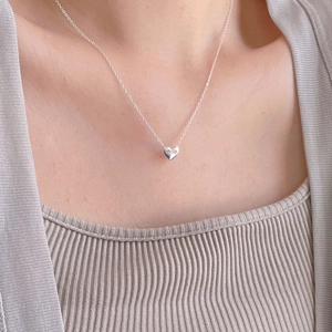 Detail of 925 sterling silver heart necklace with crystal on a woman's collarbone