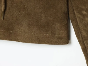 Détail d'une veste en daim marron avec cordon de serrage et embouts métalliques de qualité