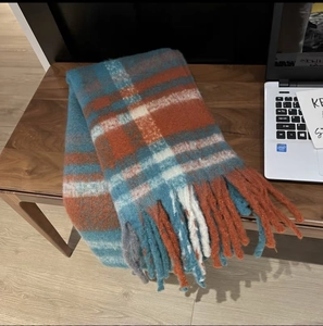 Detail of thick plaid scarf with teal and rust red checks and long fringe tassels