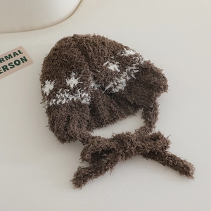 Detailed close-up of brown plush knit hat with white snowflake pattern and chin straps