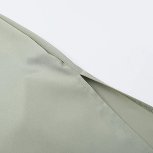 Détail de la fente latérale sur une robe en satin vert sauge avec finitions de couture