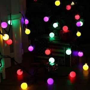 Colorful LED globe string lights glowing on white fence for outdoor camping decor