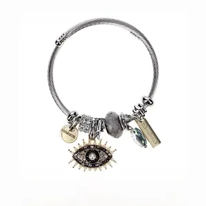 Detail of evil eye charm with micro-pave crystals on stainless steel cable bracelet