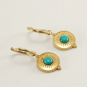 Détail de boucles d'oreilles bohèmes dorées avec motif soleil et pierre turquoise