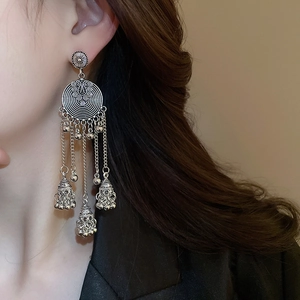 Macro shot of ethnic style silver tassel earrings with round spiral patterns on model