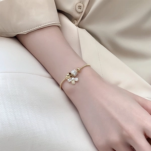 Elegantes goldenes Schlangenkette-Armband mit Zirkon-Biene und Würfelanhänger am Handgelenk