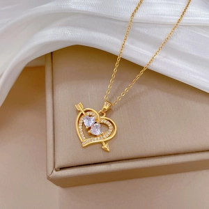 Detailed view of gold heart necklace with arrow design and pavé diamonds on silk