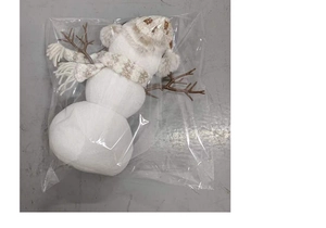 Detail view of a plush white snowman toy with knit earmuffs in transparent packaging