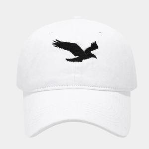 Gros plan d'une casquette blanche délavée avec broderie détaillée d'un aigle noir de face