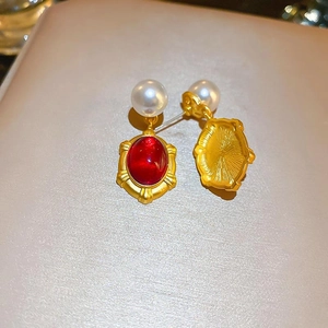 Detail of vintage gold earrings with red oval resin gemstone and white faux pearl