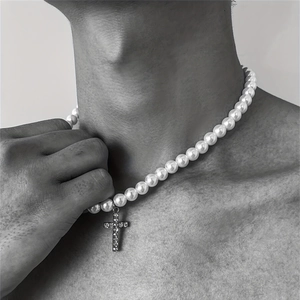 Close-up of hip-hop pearl necklace with a sparkling rhinestone cross pendant on a model