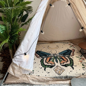Detail of bohemian woven blanket featuring butterfly and moon motifs with fringe edges
