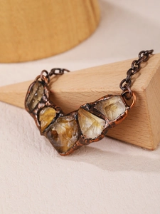 Macro detail of raw yellow citrine stone pendant with vintage bronze metallic texture
