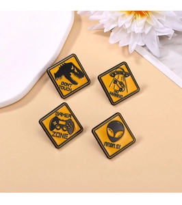 Detailed close-up of four yellow warning-style enamel pins featuring gamer and alien motifs