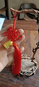 Macro-detail van rode Chinese knoopkwast met gegraveerde gouden cilinder hanger charm