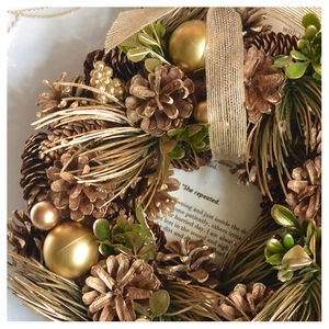Close-up of Christmas wreath with natural pine cones, gold balls and vintage book pages