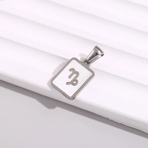 Macro shot of silver Capricorn zodiac square pendant on a wavy white and gray background