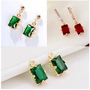 Close-up of emerald green and deep red rectangular gemstones with gold metal base