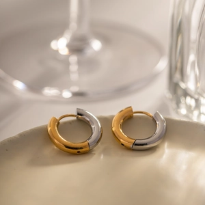 Two-tone 18k gold plated stainless steel hoop earrings on a ceramic dish