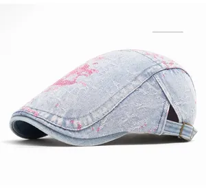 Dettaglio del berretto in denim lavato azzurro con macchie rosa e fibbia in metallo