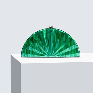 Macro shot of emerald green marble acrylic clutch bag with radial texture on white podium