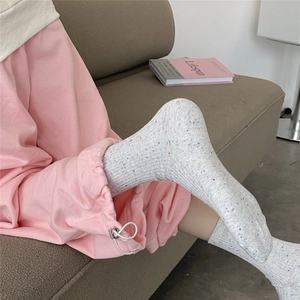 Close-up of light grey crew socks with multicolored speckles on a soft knit fabric