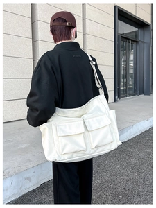 Detailed back view of cream canvas tote bag with dual front pockets and wide strap