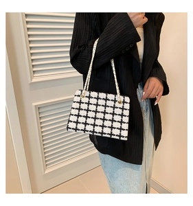 Detail of elegant black and white plaid tweed crossbody bag with gold chain strap