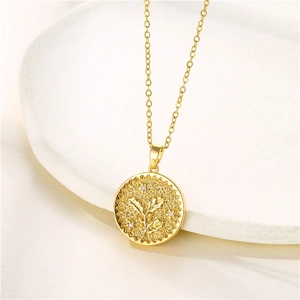 Close-up of gold coin pendant with embossed floral pattern and sparkling cubic zirconia