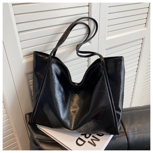 Gros plan sur le cabas en cuir PU noir montrant la texture cirée et les plis