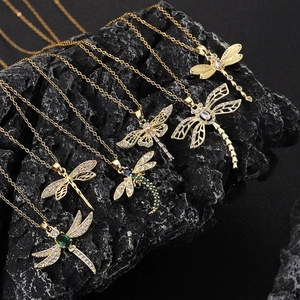 Gold dragonfly pendant necklaces with colorful zircon stones on a black rock background