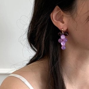 Close-up detail of elegant purple resin grape tassel earrings worn on a female model's ear