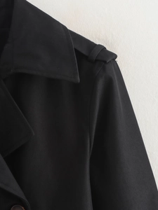 Détail des épaulettes et du revers sur un trench-coat noir classique à double boutonnage
