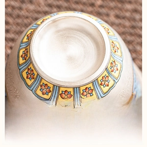 Macro shot of silver-gilt teacup detail showing intricate floral enamel and ceramic texture