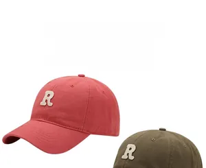 Close-up of washed cotton baseball caps with embroidered R patches in brick red and army green