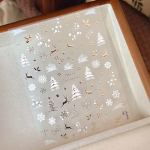 Stickers ongles Noël dorés avec cerfs et flocons de neige en relief sur fond de bois