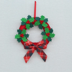 Christmas wreath wall hanging with red berries, holly leaves and plaid bow decoration