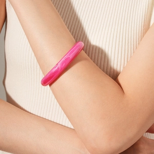 Detail of rose pink marble resin bangle with cloud-like texture on a model's wrist