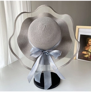 Detailed close-up of wide brim straw hat featuring a blue ribbon bow and woven texture