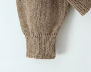 Macro shot of ribbed knit cuffs on a brown cardigan showing premium wool blend texture