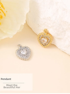 Detailed shot of gold and silver heart pendants with cubic zirconia on a stone surface
