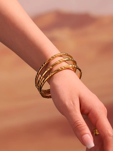 Close-up of three-piece 18K gold-plated stainless steel bangles with bamboo texture design