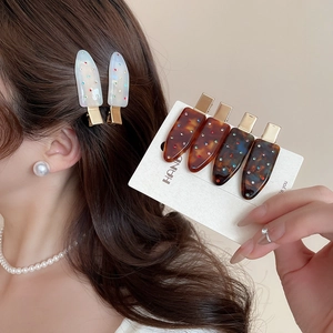 Detailed view of acrylic duckbill clips with rhinestones in white and tortoiseshell pattern