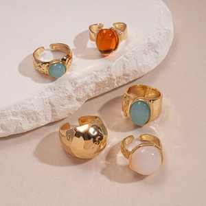 Detail view of five-piece set gold-tone resin geometric rings on natural white stone
