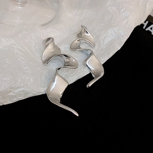 Detailed close-up of silver spiral earrings with polished finish on black and white fabric