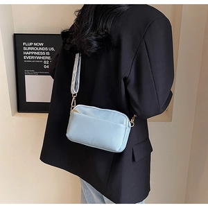 Detail of light blue PU leather crossbody bag with blue and white striped fabric strap