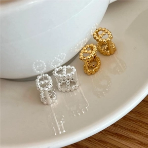Detailed view of silver and gold beaded CD shaped stud earrings on a ceramic bowl edge